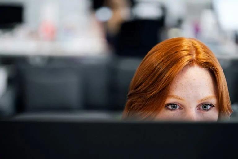 Image of female coder looking at computer screen.