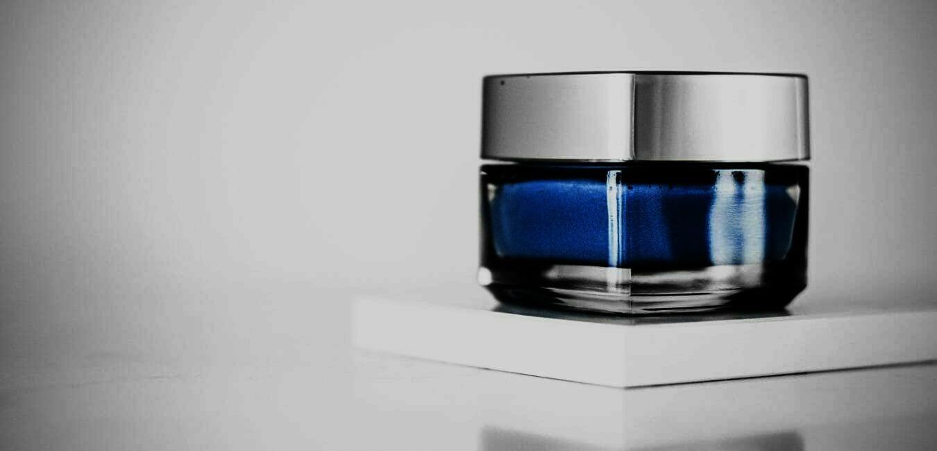 Image showing a skincare product in a blue glass jar without any labeling.