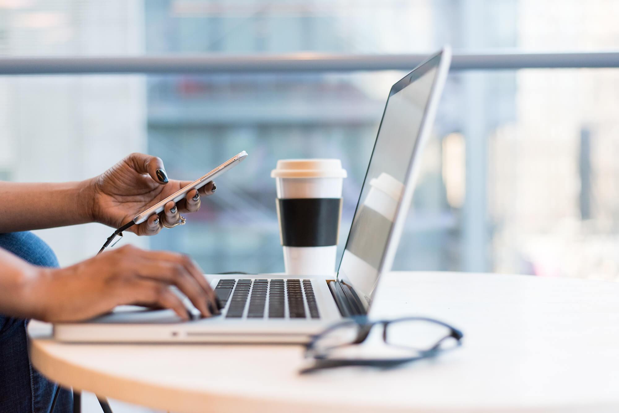 Photograph of someone viewing a web application while also using a laptop.
