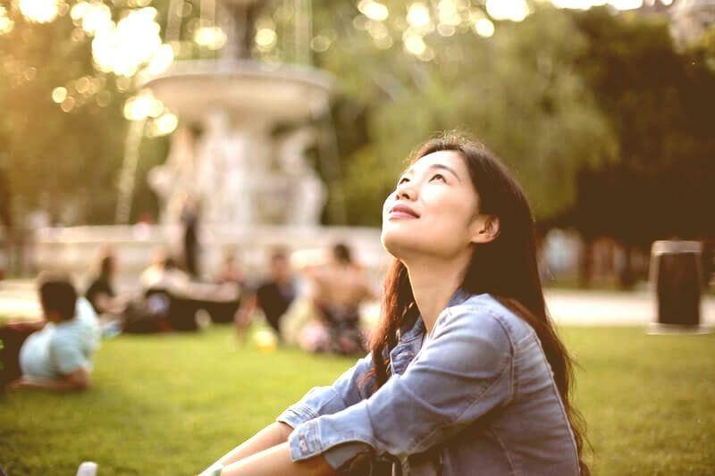 Woman in blue denim jacket sitting on green grass field antique.